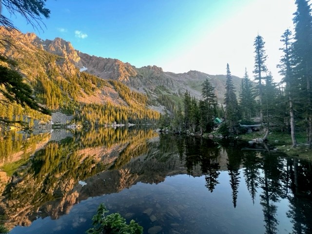 alpine lake with trees on the right and mountain on the left